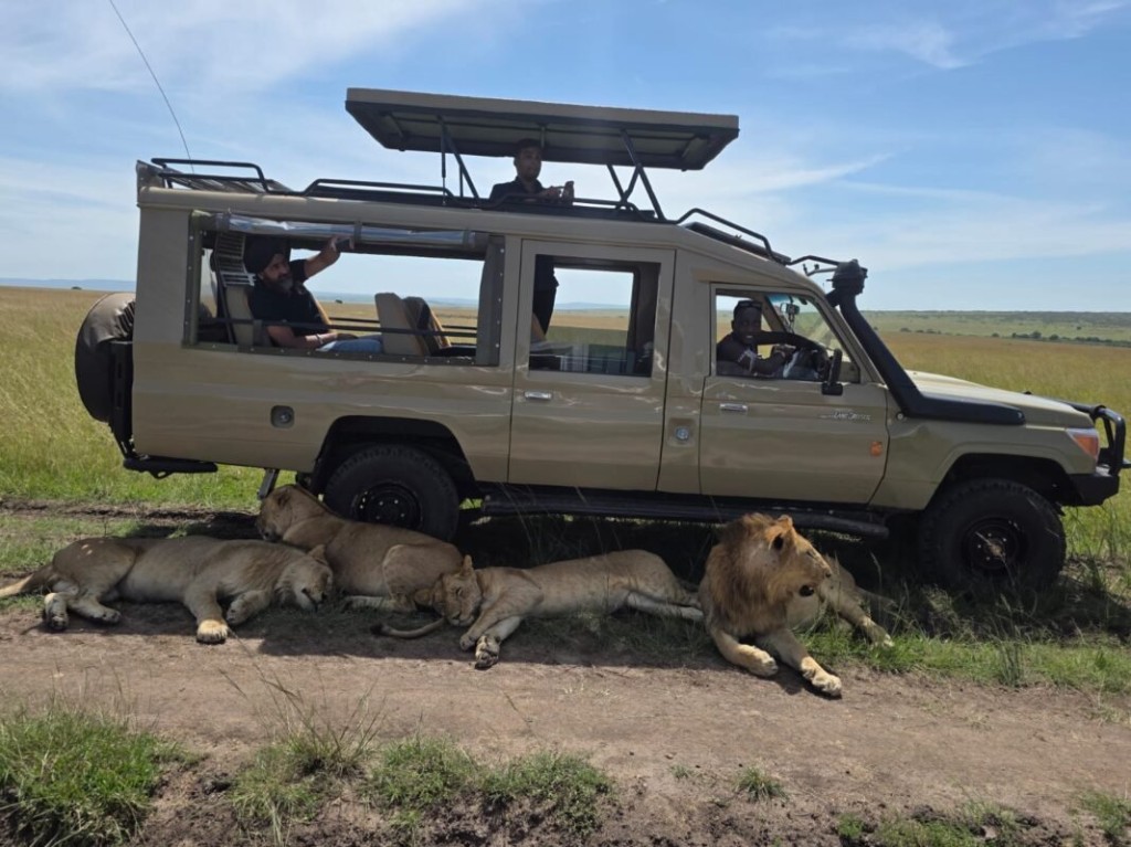 Open-roof Land Cruiser parked on a Murchison Falls game track with guests standing